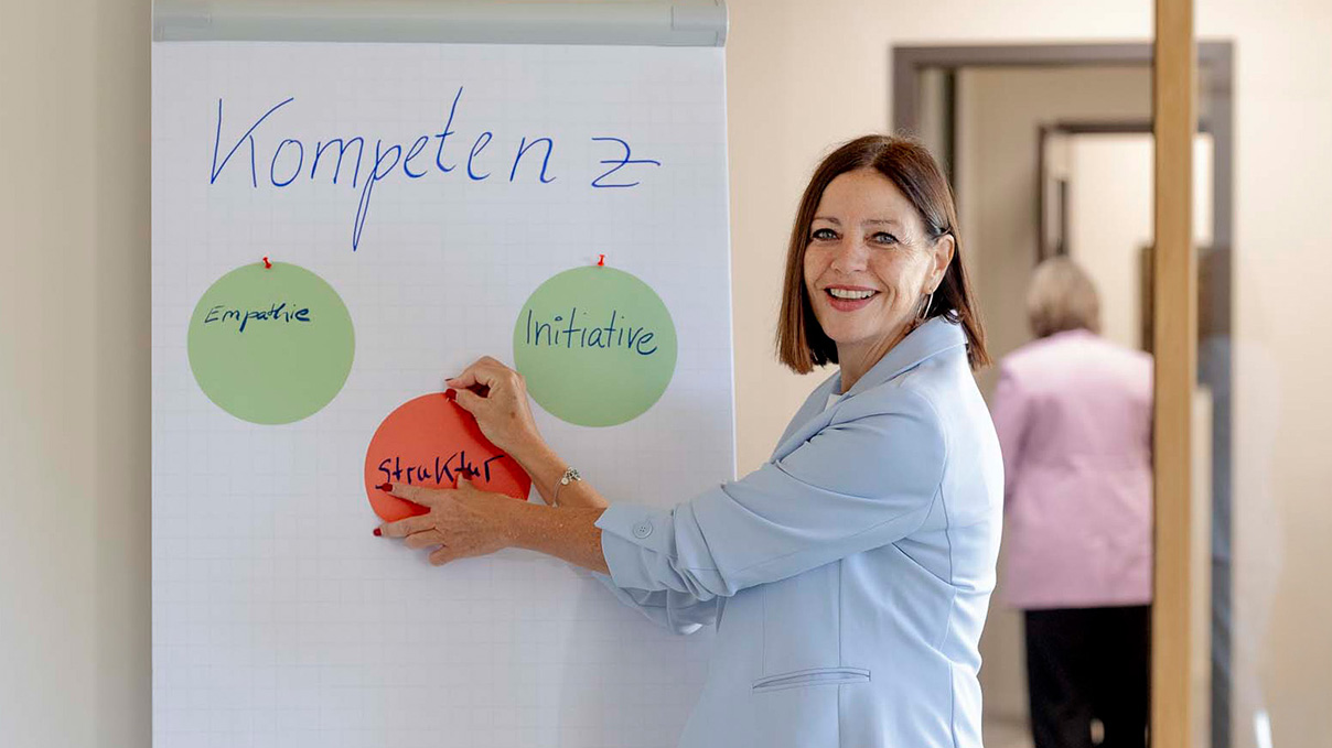 Eine Frau vor einem Flipchart, die referiert.
