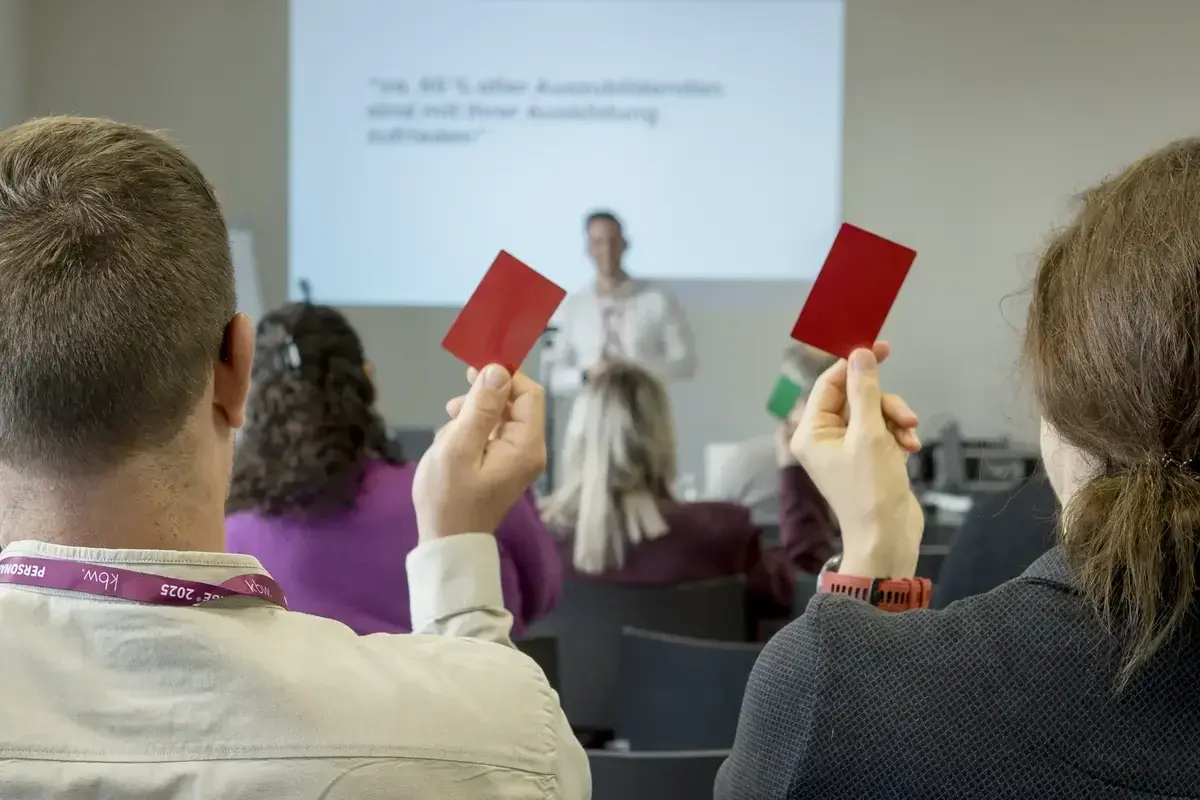 Teilnehmende halten Abstimmungskarten hoch