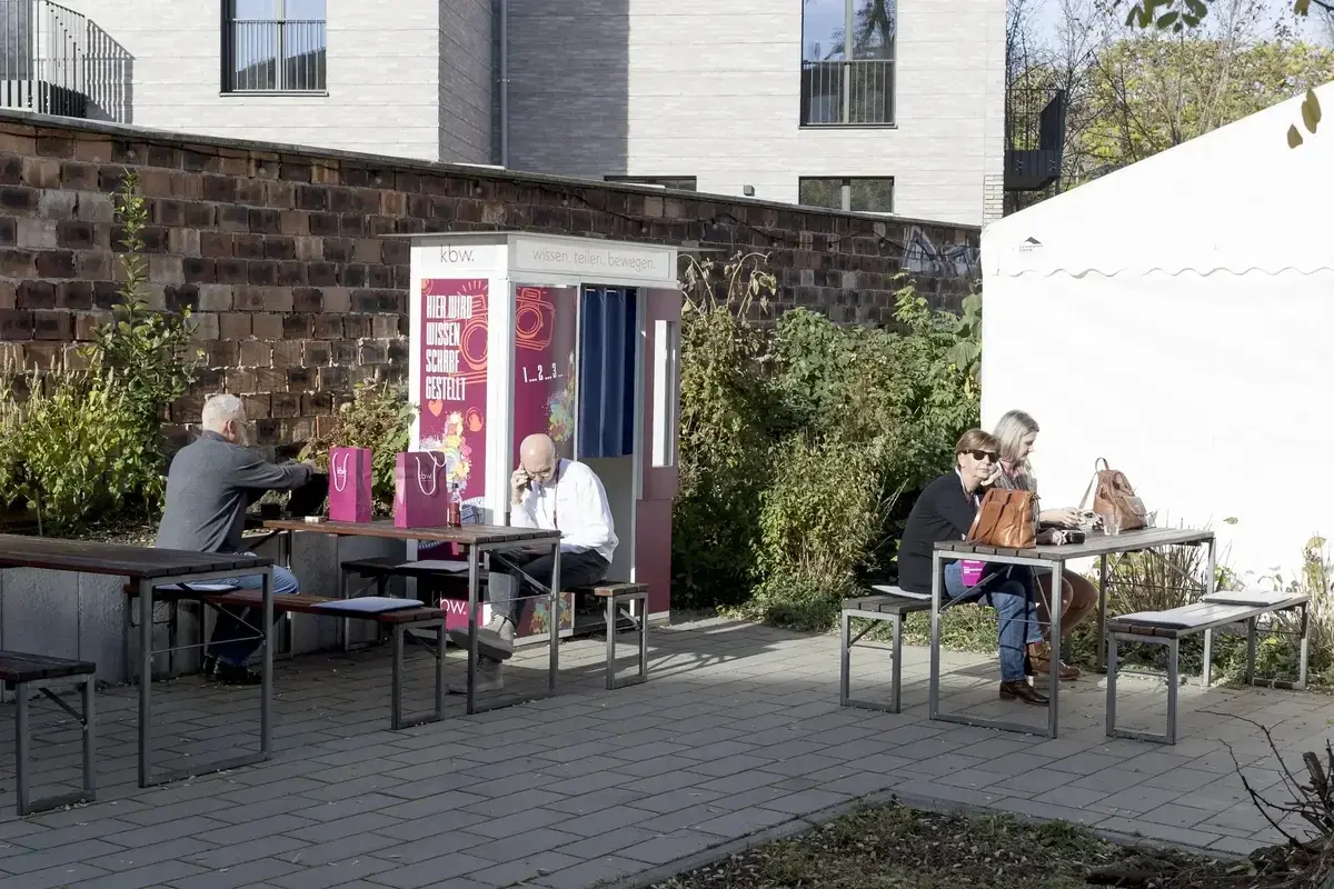 Gäste sitzen auf der begrünten Terrasse auf Bierbänken