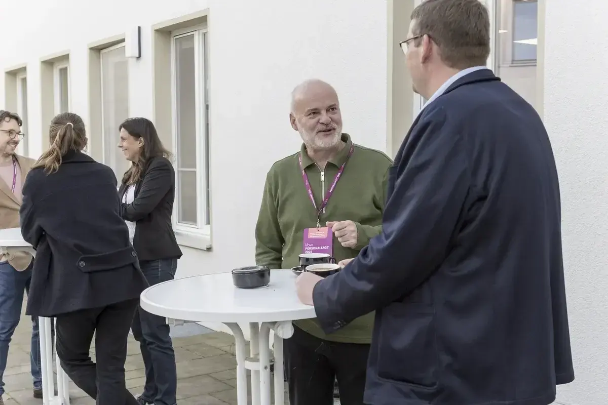 Gäste unterhalten sich an Stehtischen im Außenbereich